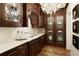 Elegant wet bar with dark wood cabinetry, marble countertop, glass shelving, and decorative chandelier at 0 Winterthur, Sandy Springs, GA 30328
