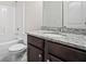 Bathroom with granite countertop, dark cabinets, white toilet, and tub with white subway tile surround at 255 Lotus Ln, Covington, GA 30016