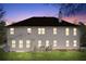 Back exterior at dusk, featuring a well-lit home, a spacious yard, and cozy patio furniture at 3920 Vine Gate Dr, Lithonia, GA 30038