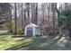 Backyard shed offering extra storage space, surrounded by mature trees and green grass at 3920 Vine Gate Dr, Lithonia, GA 30038