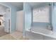Bright bathroom featuring a soaking tub, window, and tile floor at 3920 Vine Gate Dr, Lithonia, GA 30038