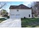 Side exterior showcasing the two-car garage and extended driveway, surrounded by lush greenery at 3920 Vine Gate Dr, Lithonia, GA 30038