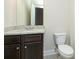 Bathroom with granite countertop vanity, dark cabinetry, and white toilet at 211 Lotus Ln, Covington, GA 30016