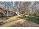 View of the tan house and large backyard space dotted with daffodils and bordered by trees at 58 Knox Rd, Powder Springs, GA 30127