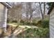 Backyard view of home adjacent to shed, complemented by a concrete walkway and natural landscaping with daffodils at 58 Knox Rd, Powder Springs, GA 30127