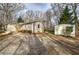 Exterior view of a charming home and adjacent shed, complemented by a gravel driveway and natural landscaping at 58 Knox Rd, Powder Springs, GA 30127