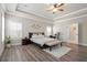 Spacious main bedroom featuring tray ceilings, a ceiling fan, wood-look flooring, and natural light from many windows at 6180 Bellmoore Park Ln, Duluth, GA 30097