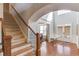 Staircase in the foyer featuring hardwood steps, with large windows allowing ample natural light to illuminate the space at 5732 Ashleigh Walk Dr, Suwanee, GA 30024