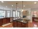 Open concept kitchen with center island, wood floors, stainless appliances, and a cozy living area at 5732 Ashleigh Walk Dr, Suwanee, GA 30024