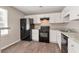 Modern kitchen features white cabinets, granite counters, black appliances and wood-look flooring at 600 Canterbury Ln, Lawrenceville, GA 30046