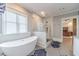 Luxurious main bathroom with a soaking tub, glass-enclosed shower, and stylish tile flooring at 2418 Claude Brewer Rd, Loganville, GA 30052