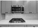 Close-up of a kitchen with gas range, microwave, and white subway tile backsplash at 2784 Hilson Commons, Decatur, GA 30034