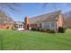 Backyard view of brick home with a large green lawn and mature landscaping at 223 Ivy Creek Dr, Loganville, GA 30052