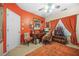 Bright home office featuring a wooden desk and chair set against a vibrant orange wall at 165 Babbling Brook, Mcdonough, GA 30252