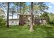 Backyard featuring a lawn, mature trees, and a side-entry garage attached to the house at 3973 Elmscourt Dr, Stone Mountain, GA 30083