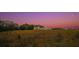 A beautiful farmhouse at sunset sits on a hill with a large lawn and separate outbuilding at 774 Forrester Cemetery Rd, Covington, GA 30014