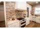 Well-equipped kitchen featuring white cabinetry, modern stove, and stylish brick accents at 774 Forrester Cemetery Rd, Covington, GA 30014