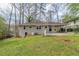 Rear view of home featuring light colored exterior, carport, and spacious grassy yard at 1624 Linda Dr, Decatur, GA 30032