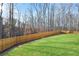 Wide shot of a green backyard with a tall wooden privacy fence and a wooded area in the background at 441 Ajo Way, Dallas, GA 30157