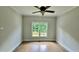 Bright bedroom featuring hardwood floors, ceiling fan, and a window with green outdoor views at 838 Natchez Valley Trce, Grayson, GA 30017