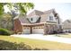 Elegant home with a three-car garage, brick and stone accents, and a spacious driveway surrounded by mature trees at 838 Natchez Valley Trce, Grayson, GA 30017