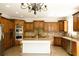 Well-lit kitchen with custom wood cabinets, stainless steel appliances, a granite island, and stylish chandelier at 838 Natchez Valley Trce, Grayson, GA 30017