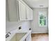 Well-lit laundry room with ample storage space, sink, and large window at 838 Natchez Valley Trce, Grayson, GA 30017