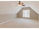 View of the carpeted attic area with updated lighting and a window at 283 Double Gate Way, Sugar Hill, GA 30518