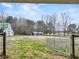 Spacious fenced-in yard features verdant grass, mature trees, and metal gate, offering privacy and country charm at 3121 Cox Cemetery Rd, Social Circle, GA 30025