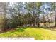 Backyard showcasing a lush green lawn and mature trees, offering a serene and private outdoor space at 9122 Golfview Cir, Covington, GA 30014