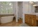 Bathroom featuring standalone tub, tiled floors, separate toilet room and wooden vanity under lighted mirror at 6029 Shadburn Ferry Rd, Buford, GA 30518
