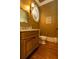 Charming powder room featuring wood floors, custom vanity and a unique mirror, plus abundant lighting at 6029 Shadburn Ferry Rd, Buford, GA 30518