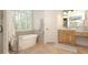 Elegant bathroom featuring a standalone tub, tiled floors, and a wooden vanity under a lighted mirror at 6029 Shadburn Ferry Rd, Buford, GA 30518