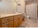 Bathroom featuring a marble vanity with honey colored cabinets, framed mirror, and shower with tile surround at 6029 Shadburn Ferry Rd, Buford, GA 30518