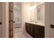 Bathroom showcasing a dark vanity with dual sinks and a connecting hallway to a bedroom at 6029 Shadburn Ferry Rd, Buford, GA 30518