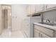 Laundry room with white appliances, cabinets, tile floors and utility sink at 950 Sundew Se Dr, Conyers, GA 30013