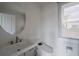 Modern bathroom features a sleek toilet, elegant sink with a unique round mirror and a bright window at 1049 Brandsford Nw St # 27-01, Atlanta, GA 30318