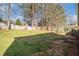 Spacious backyard with green grass, mature trees, and a wood fence under a bright sky at 142 Parkside Dr, Stockbridge, GA 30281