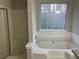 Bathroom featuring a tub with white tile surround, shower, and a window with a wooded view at 6023 Kingston Wood Way, Lithonia, GA 30038