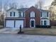 Two-story home featuring brick and siding, a two-car garage, and manicured landscaping at 6023 Kingston Wood Way, Lithonia, GA 30038