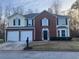 Two-story home featuring brick and siding, a two-car garage, and manicured landscaping at 6023 Kingston Wood Way, Lithonia, GA 30038