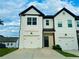 Charming townhome featuring a two-car garage, black roofline and a well-maintained front lawn at 124 Auburn Run Ln, Auburn, GA 30011