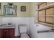 Small, simple bathroom with a dark wood vanity, toilet, and a window with frosted glass for privacy at 799 Moreland Se Ave, Atlanta, GA 30316