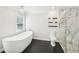 A bathroom featuring black tile floors, a modern soaking tub and glass shower with marble style walls at 1600 Spring Arbor Sw Ct, Lilburn, GA 30047