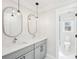 A bathroom featuring double sinks with grey cabinetry, oval mirrors, modern fixtures, and a door to the water closet at 1600 Spring Arbor Sw Ct, Lilburn, GA 30047