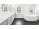 A bathroom featuring double sinks with grey cabinetry, black hardware, black tile floors, and a modern soaking tub at 1600 Spring Arbor Sw Ct, Lilburn, GA 30047