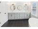 A bathroom featuring double sinks with grey cabinetry, black hardware, black tile floors, and oval mirrors at 1600 Spring Arbor Sw Ct, Lilburn, GA 30047