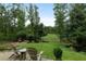 Serene backyard view featuring a gravel patio with Adirondack chairs overlooking a lush green lawn at 7455 Old Rico Rd, Chattahoochee Hills, GA 30268