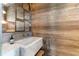 Stylish powder room with marble sink, brass fixtures and wood paneled wall at 7455 Old Rico Rd, Chattahoochee Hills, GA 30268