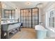 Bright bathroom with stone floors, double sink vanity, walk-in shower, and a standalone soaking tub at 7455 Old Rico Rd, Chattahoochee Hills, GA 30268